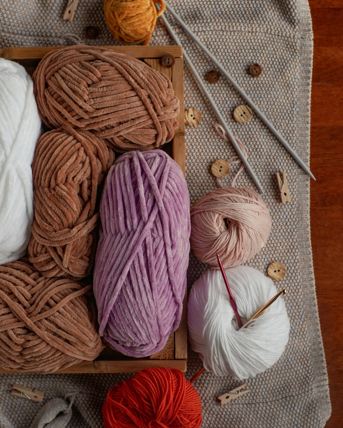 A wooden box filled with balls of yarn and knitting needles