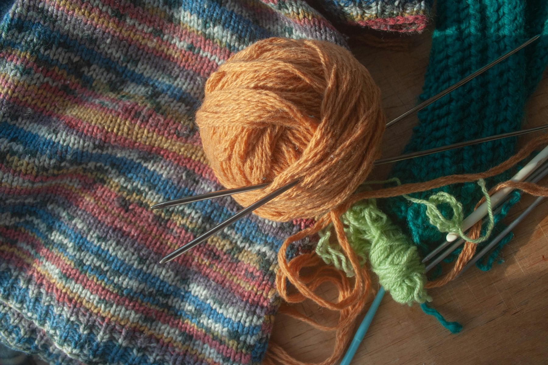 A ball of yarn and knitting needles on a wooden table